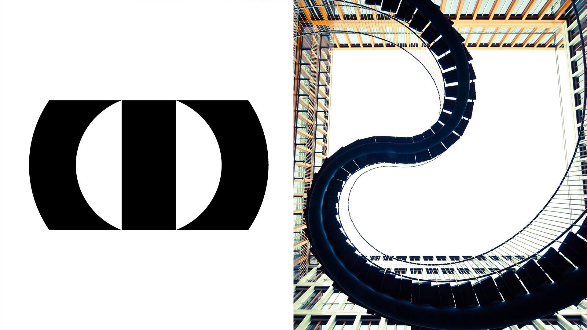 Upward view of a spiral staircase framed by glass and steel architecture